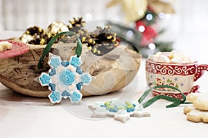Christmas cookies shaped in snowflakes and golden cones. Hot chocolate with marshmallow candies. White wooden background