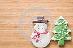 Christmas cookies, snowman, X`mas tree, gingerbread flat lay on wooden cutting board background top view for X`mas party holiday