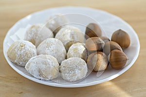 Christmas cookies, tasty balls with hazelnut inside and icing sugar, white plate and wooden table