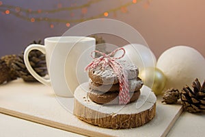 Christmas cookies tied with a New Year`s ribbon lie on a wooden stand and a board with flour near a white mug, Christmas