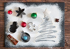 Christmas cooking. Xmas tree made from flour on a dark table, ingredients for baking on dark background, top view