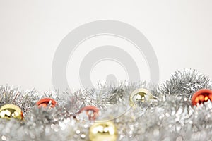 Christmas copy space with red and gold bright baubles in silver decorative chain on bottom on white background and bokeh effect