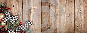 Christmas corner border banner with white and black checked buffalo plaid ribbon, baubles and branches, above on a wood background