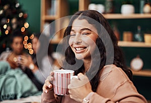 Christmas is the cosiest times of the year. a beautiful young woman enjoying a warm beverage with her friends in the