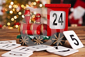 Christmas countdown. Wooden train Christmas advent calendar, with tree lights bokeh.