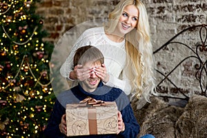 Christmas couple, happy young female surprise man cover his eyes