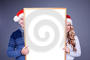 Christmas couple holding white board with empty