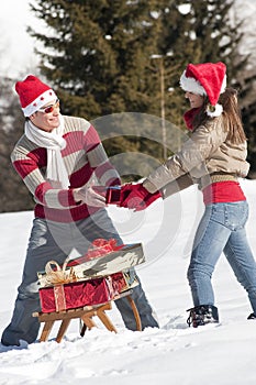 Christmas couple playing with gifts in the snow