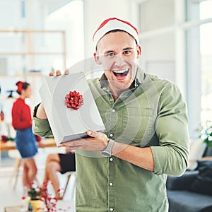 Christmas, coworking office and gift for excited and happy business man during holiday celebration with secret Santa