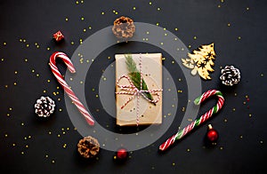 Christmas craft gift boxes with red ribbons, pine cones and red and golden decorations against black background