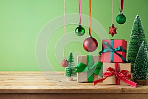 Christmas creative concept with gift boxes composition as Christmas tree and hanging ornamnet decoration on wooden table over