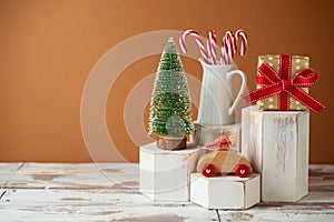 Christmas creative concept with toy car, pine tree and gift box on geometric podium on wooden table