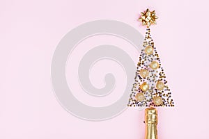 Christmas creative fir tree from champagne, confetti stars, serpentine and golden balls on pink background top view. Flat lay.