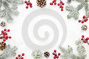 Christmas creative frame made of cones, red berry and fir branches on white background with free space for lettering