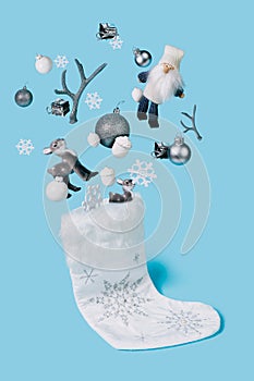 Christmas creative layout made with sock and flying bauble tree balls, antlers, Santa Claus and reindeer on blue background