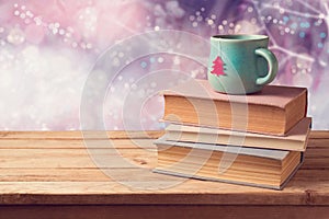 Christmas cup of tea and vintage books on wooden table over beautiful winter bokeh background with copy space