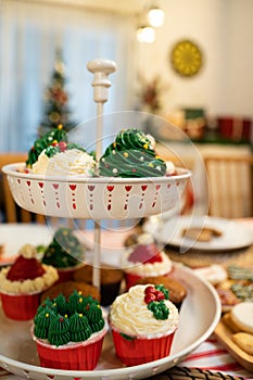 Christmas cupcake set with pine tree and Santa hat design homemade sweet dessert on a family dinner table for eat after meal in