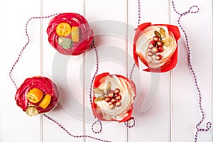 Christmas cupcakes with decorations, top view. Holidays card with cupcakes on white wooden background