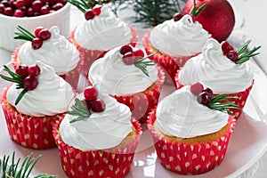 Christmas cupcakes with vanilla frosting, cranberries and rosemary