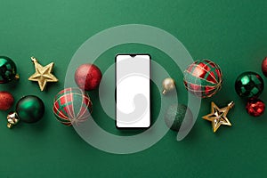 Christmas Day concept. Top view photo of smartphone star ornaments gold green and red baubles on isolated green background with