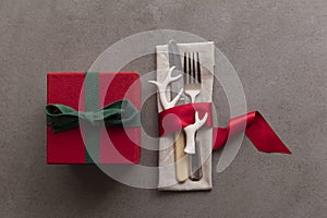 Christmas day table setting with cutlery wrapped in a red ribbon and gift box presents