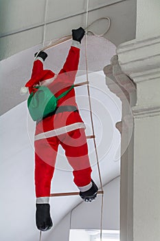 Christmas decor. Decorative Santa Claus with gifts climbs the rope ladder