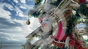 Christmas decor hanging on eco-friendly Xmas tree colours red and white at tropical white sand beach in paradise
