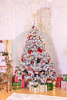 Christmas decor of the living room . the decoration of the room. Christmas snow-covered fir tree with toys. gift boxes under the