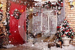 Christmas decor on a patio. Doors are decorated by a festive chaplet and toys. Fir-tree at a window