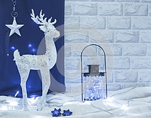 Christmas decor white deer with dark and glass lantern and lights on blue and white background in colour of the year 2020 Classic