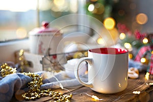 Christmas decor by the window on a cozy wooden windowsill with a mug with a drink and a cookie jar. Fairy lights, Christmas tree