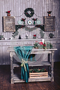 Christmas decor in a wooden house. The shelf is decorated with a garland and fir branches. Wooden table with roses and candles