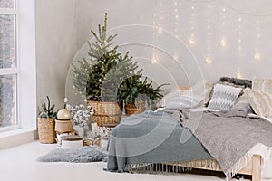 Christmas decorated bedroom interior with comfortable bed, Christmas fir tree and gift boxes on floor, copy space. Cozy home