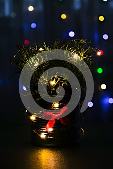 Christmas decorated eco christmas tree in metal jar with bokeh lights on background in living room at night. Zero waste