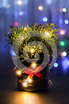 Christmas decorated eco christmas tree in metal jar with bokeh lights on background in living room at night. Zero waste