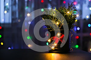 Christmas decorated eco christmas tree in metal jar with bokeh lights on background in living room at night. Zero waste