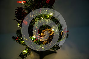 Christmas decorated small tree with red and gold decorations slowly lights up a light chain wrapped around a tree of yellow color photo