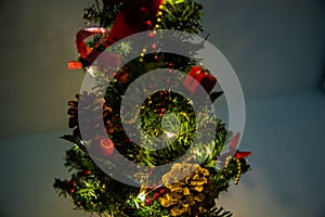 Christmas decorated small tree with red and gold decorations slowly lights up a light chain wrapped around a tree of yellow color photo