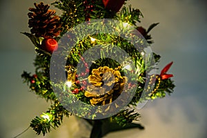 Christmas decorated small tree with red and gold decorations slowly lights up a light chain wrapped around a tree of yellow color photo
