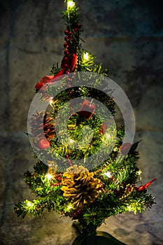 Christmas decorated small tree with red and gold decorations slowly lights up a light chain wrapped around a tree of yellow color photo