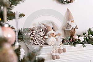 Christmas decorated tree in soft pink colors against the background of white classic fireplace with Christmas decorations. Details