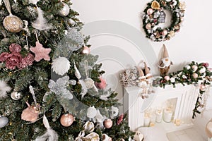 Christmas decorated tree in soft pink colors against the background of white classic fireplace with Christmas decorations. Details