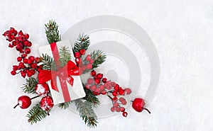 Christmas decoration, banner. Gift box with red ribbon, bow, twigs christmas tree, red berries and apples on snow