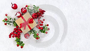 Christmas decoration, banner. Gift box with red ribbon, bow, twigs christmas tree, red berries and apples on snow