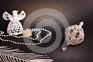 Christmas decoration on black background. White angel, candle, silver feather, beads and christmas tree bauble