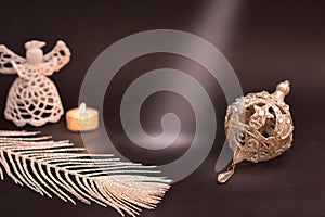 Christmas decoration on black background. White angel, candle, silver feather and christmas tree bauble, Light ray on free space