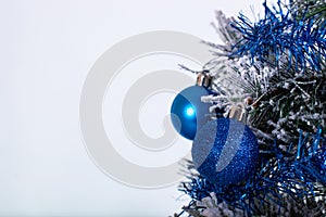 Christmas decoration blue and silver balls in a tree with tinsel and pinecone in snow