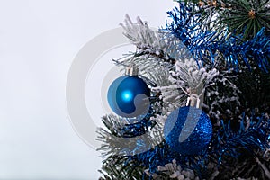 Christmas decoration blue and silver balls in a tree with tinsel and pinecone in snow