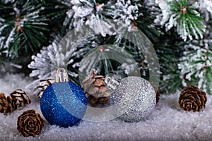 Christmas decoration blue and silver balls in a tree with tinsel and pinecone in snow