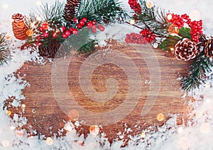 Christmas decoration, branch of fir tree with cones and snow on wooden background.Merry Christmas and Happy New Year theme.